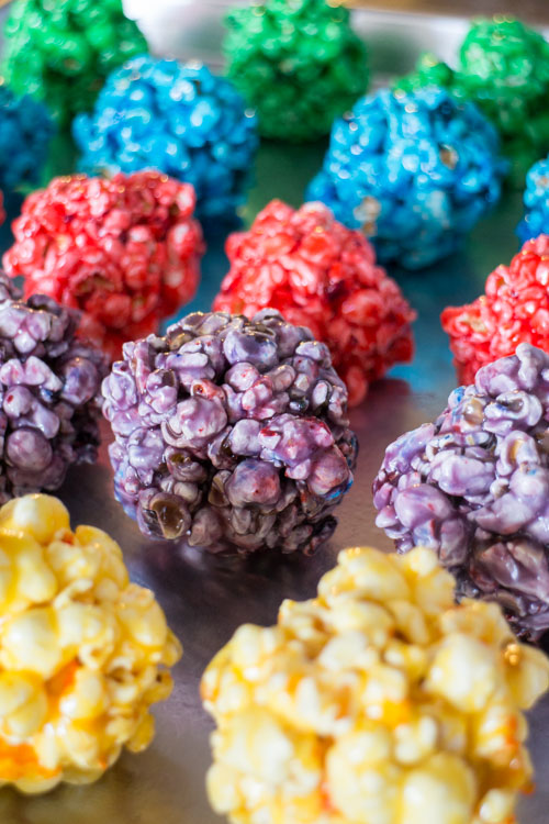 How to Make RAINBOW Popcorn Balls! This easy DIY recipe walks you through how to make these marshmallow popcorn balls that are colored using food dye and karo syrup! They