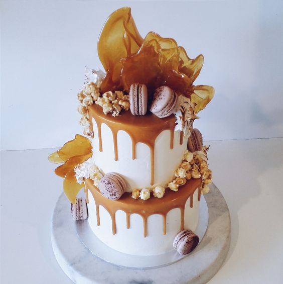 2 tier white buttercreme & caramel drip cake with macarons, popcorn & cascading toffee shards